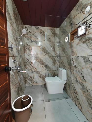 a bathroom with a toilet and a glass shower at Bella Casa Beach Resort in Varkala
