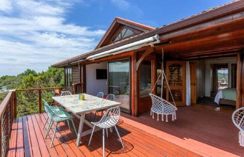 a wooden deck with a table and chairs on it at Loerie's Rest Cabin in Victoria Bay