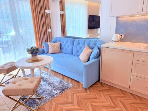 un salon avec un canapé bleu et une table dans l'établissement Apartament Holiday Aqua Crystal, à Rewal