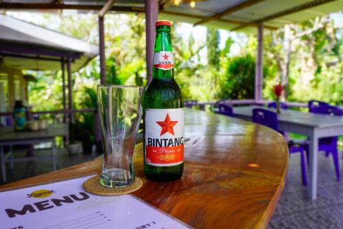a bottle of beer sitting on a table with a glass at Legend Guesthouse in Kelimutu