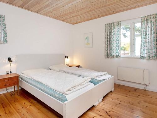 a white bedroom with a bed and a window at Beachside Haven in Marielyst - By Traum Ferienwohnungen in Marielyst