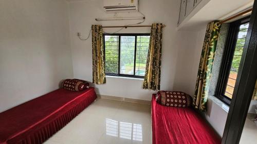 two red beds in a room with two windows at Nakshatra in Sawantwadi