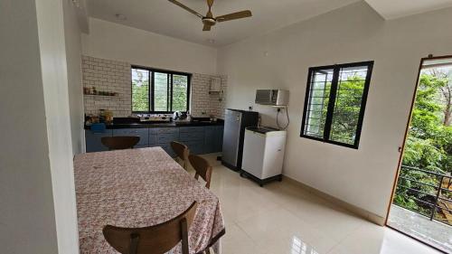 a kitchen with a table with chairs and a refrigerator at Nakshatra in Sawantwadi