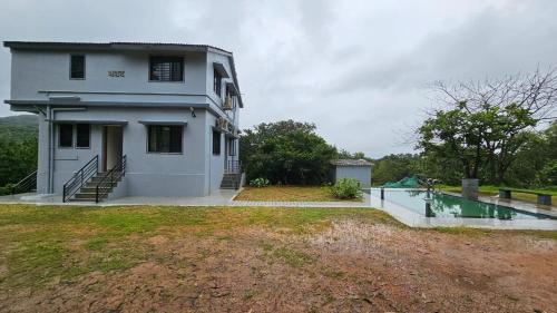 a white house with a pool in front of it at Nakshatra in Sawantwadi