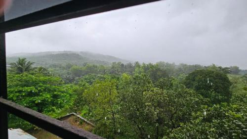 a view of a forest with mountains in the background at Nakshatra in Sawantwadi