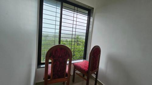 two chairs sitting in front of a window at Nakshatra in Sawantwadi