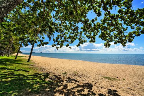 a sandy beach with trees and the ocean at Trinity Beach Club Holiday Apartments in Trinity Beach