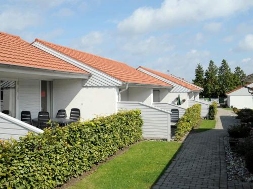 a row of white houses with chairs in a yard at 4 person holiday home in Ærøskøbing-By Traum in Ærøskøbing