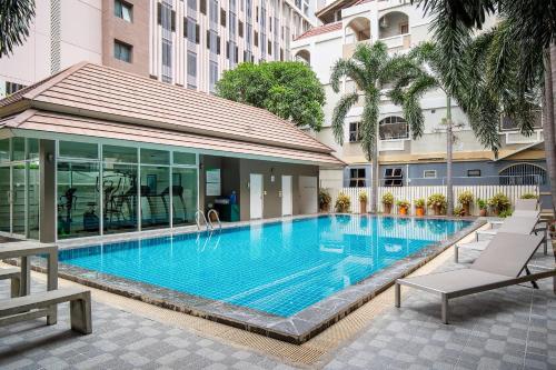 a large swimming pool with two lounge chairs next to a building at Diya Hotel Bangkok in Amphoe Phra Khanong