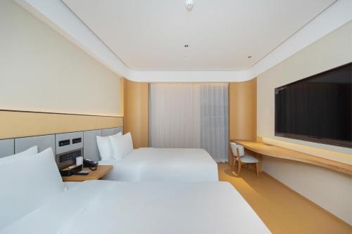 北京市にあるJi Hotel Beijing Shangdi Zhongguancun Software Parkの大きなベッドと薄型テレビがあるホテルの部屋