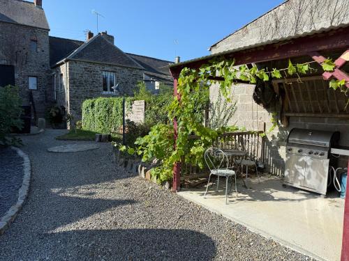 a patio of a house with a table and some vines at La Roulotte de Ville Chérel in Pontorson