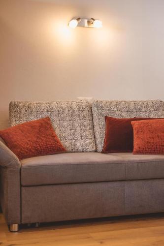 a gray couch with two pillows on it at Appartements Bucher in Brixen im Thale