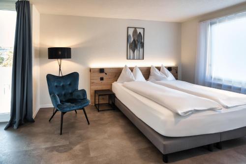 a bedroom with a large bed and a chair at Hotel Bären Suhr in Aarau