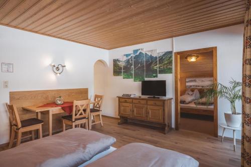 a bedroom with a bed and a table with a television at Appartements Bucher in Brixen im Thale