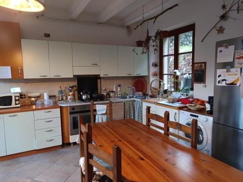 a kitchen with white cabinets and a wooden table at 2 double rooms apartment- La Casa di Alice in Valbrona