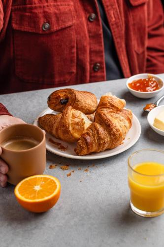 a plate of pastries and an orange on a table at Ibis Budget Sisteron in Sisteron