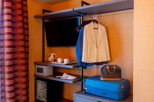 a room with a suitcase and a coat on a shelf at La Villa - Sure Hotel Collection by Best Western in Ivrea