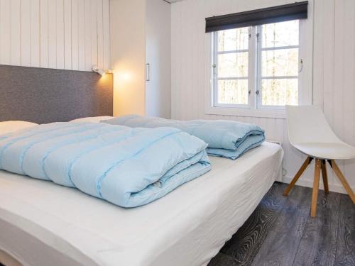 a bedroom with a bed with blue sheets and a window at 4 star holiday home in Ringkøbing in Ringkøbing