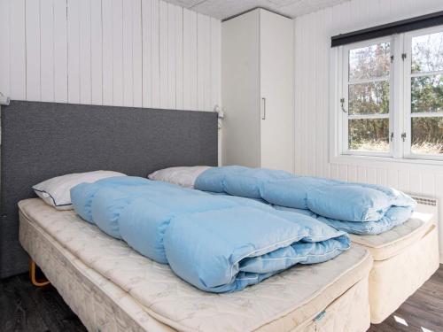 a large bed with blue pillows on top of it at 4 star holiday home in Ringkøbing in Ringkøbing