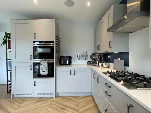 a kitchen with white cabinets and a stove top oven at Luxury 3 Bedroom Home - 15mins to Birkdale Open in Formby