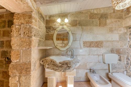 a stone bathroom with a sink and a toilet at Guest House Fontanelle in Ugento
