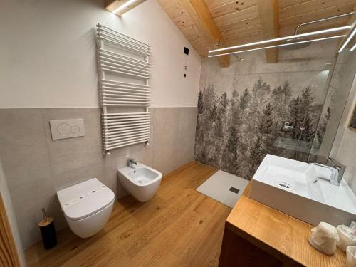 Un baño con inodoro, bidé y lavabo. en Albergo Scoiattolo, en Falcade
