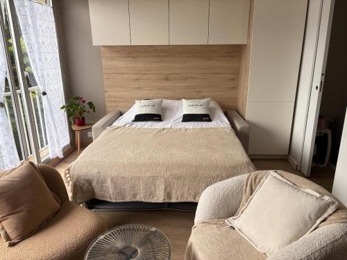a bedroom with a bed with two chairs and a fan at Escapade à la mer studio in Dinard