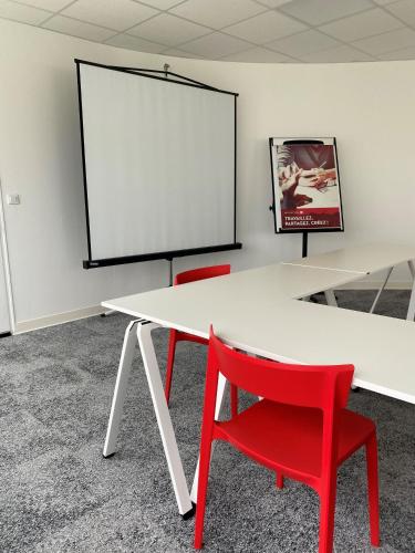 a white table with a red chair and a screen at ibis Montélimar Nord in Saulce-sur-Rhône