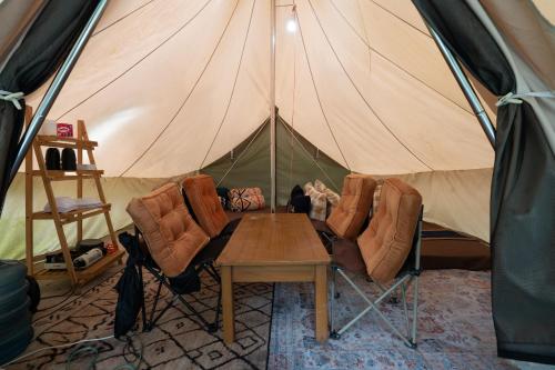 a tent with chairs and a table in front of it at Kuleum Camp And Cabin By ARBA in Baruhtunggul