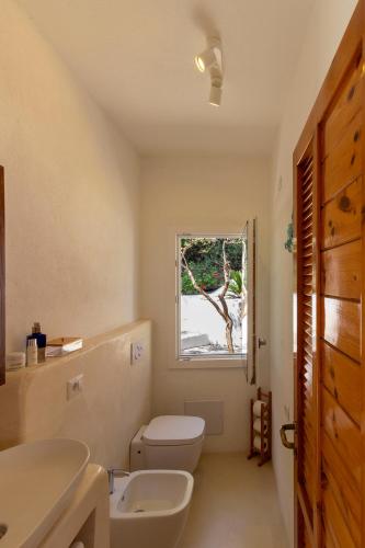a bathroom with a toilet and a sink and a window at Villa Tuna in Torre delle Stelle