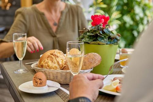 a woman sitting at a table with food and glasses of champagne at Hotel Lindenhof in Kellberg