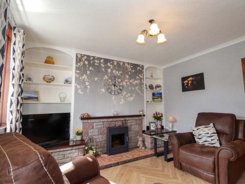 a living room with a fireplace and a tv at The Highlander in Dornie
