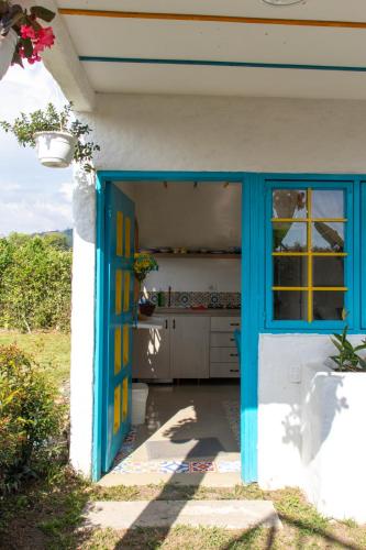 an entrance to a house with a blue door at La Trasnochadora - Duerme en una típica finca cafetera Colombiana in Pereira