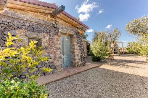 a stone house with a blue door and a yard at Guest House Fontanelle in Ugento