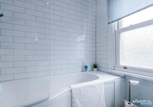 a white bathroom with a tub and a window at 5BR House, Sleeps 10 guests - Free Parking - Great for Professionals & Contractors in Pontefract