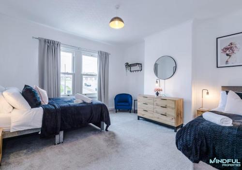a bedroom with two beds and a mirror and a chair at 5BR House, Sleeps 10 guests - Free Parking - Great for Professionals & Contractors in Pontefract