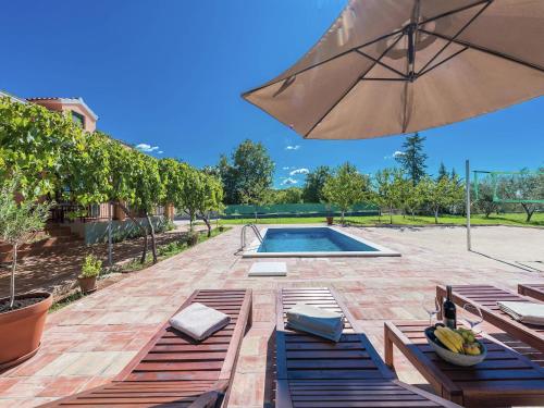 a swimming pool with benches and an umbrella at Holiday Home in Zemunik Donji with Pool in Donji Zemunik
