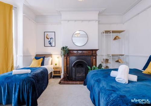 two beds in a room with a fireplace at 5BR House, Sleeps 10 guests - Free Parking - Great for Professionals & Contractors in Pontefract