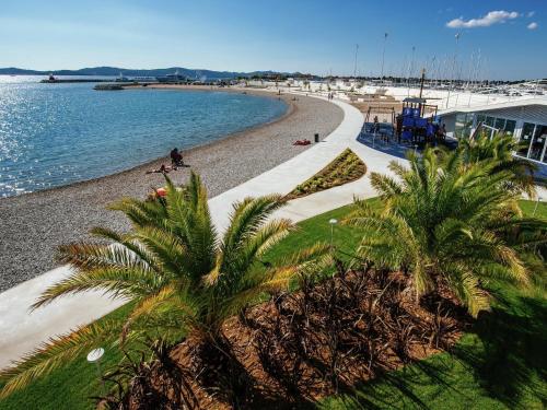 a beach with palm trees next to the water at Holiday Home in Zemunik Donji with Pool in Donji Zemunik