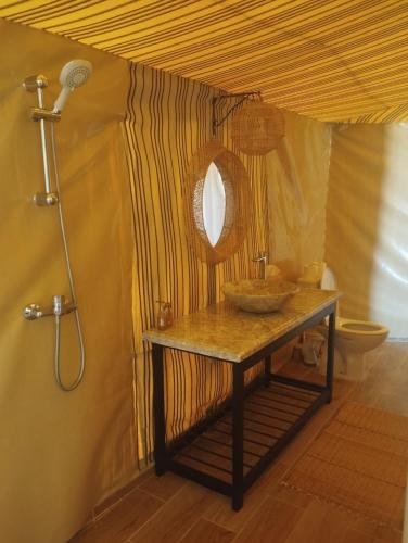 a bathroom with a table with a mirror and a shower at Kalimba Luxury Desert Camp in Merzouga