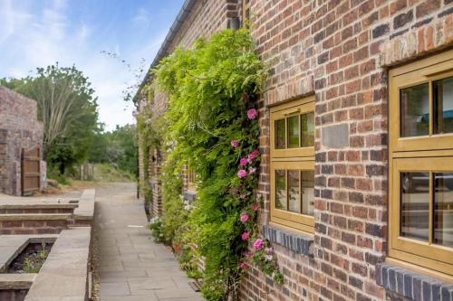 a brick building with flowers on the side of it at Caldon Barn in Stoke on Trent