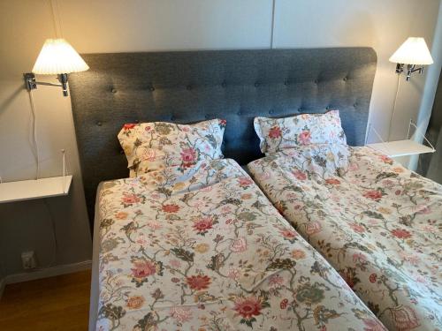 a bed with a floral bedspread and two pillows at Slimmingegården 1019 in Skurup