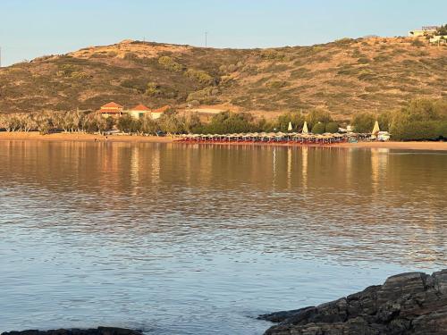 a body of water with a beach and a mountain at Art Sounion, Seafront Elegance in Sounio