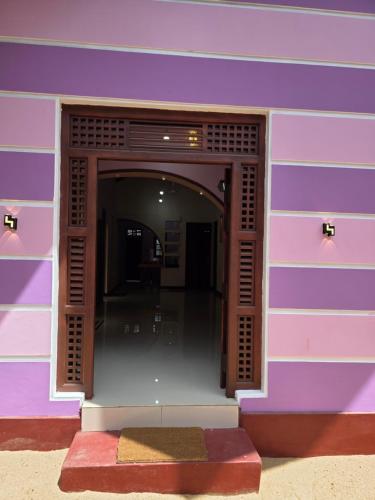 a building with a purple wall with a doorway at YAS Beach Villa in Kattankudi