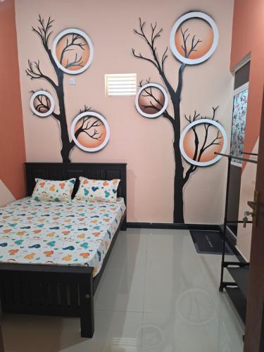 a bedroom with a bed and trees painted on the wall at YAS Beach Villa in Kattankudi
