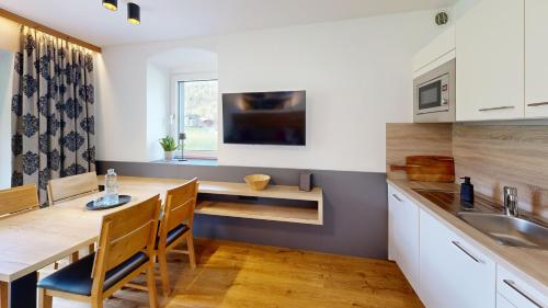 a kitchen with white cabinets and a wooden table with chairs at Appartements Am Achensee in Pertisau