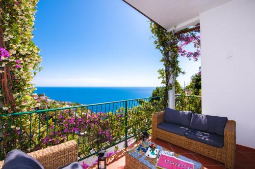 a balcony with a couch and flowers and the ocean at Hotel Pellegrino in Praiano