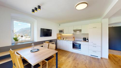 a kitchen with white cabinets and a wooden table at Appartements Am Achensee in Pertisau