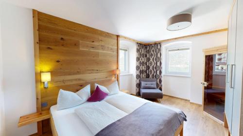 a bedroom with a white bed with a wooden headboard at Appartements Am Achensee in Pertisau
