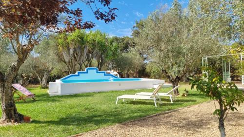 a pool in a yard with two chairs and trees at Montadinho Houses in São Bartolomeu da Serra